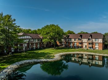 an apartment complex with a pond in front of it at Bavarian Village Apartments, Indianapolis